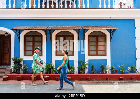 Goa, Indien -- 10. April 2023. Zwei Frauen, eine Tourist, die andere ein Einheimischer, machen einen Spaziergang in einem wohlhabenden Viertel in Goa India. Stockfoto