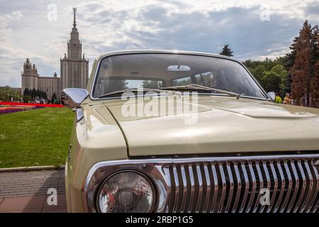 Moskau, Russland. 9. Juli 2023. Ein sowjetisches GAZ-24-Wolga-Auto ist vor dem Hintergrund des Hochhauses der Moskauer State University auf den Sparrow Hills in Moskau, Russland, zu sehen Stockfoto