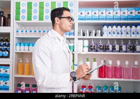 Junger hispanischer Apotheker, der auf einem Dokument in der Apotheke schreibt Stockfoto