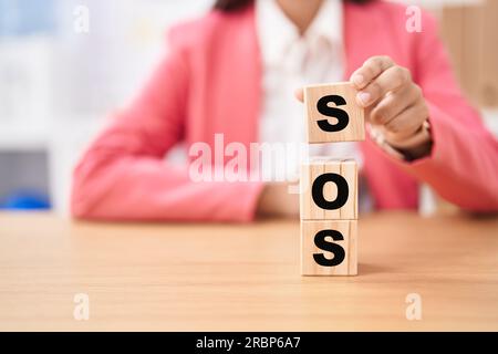 Geschäftsfrau mit Würfeln und sos-Wort auf dem Tisch Stockfoto