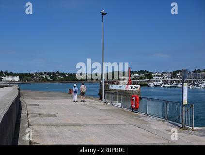 Ein Paar, das am Haldon Pier, Torquay Hafen, South Devon entlang spaziert. Stockfoto