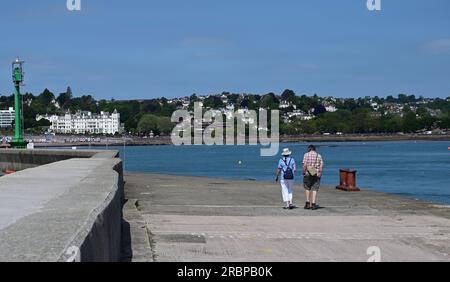 Ein Paar, das am Haldon Pier, Torquay Hafen, South Devon entlang spaziert. Stockfoto