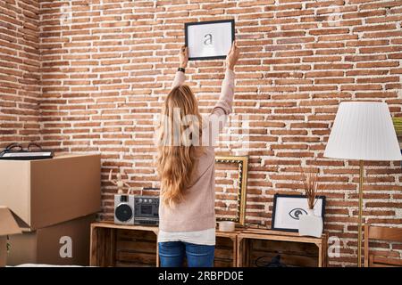 Junge Frau, die ein Bild an die Wand hängt Stockfoto