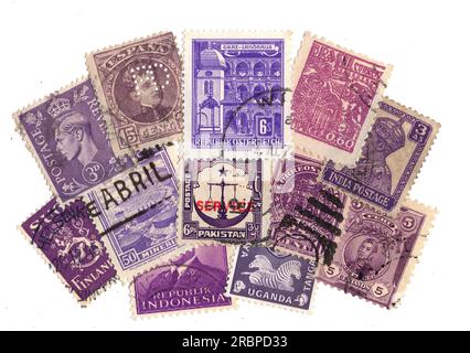 Lila Briefmarken aus aller Welt auf weißem Hintergrund. Stockfoto