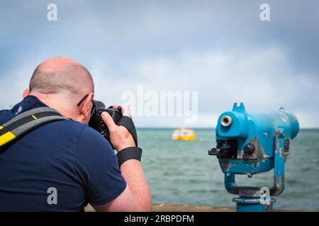 Zurück von einem Fotografen, der ein Foto von einem Boot neben einem Turm in San Francisco, Kalifornien, macht Stockfoto