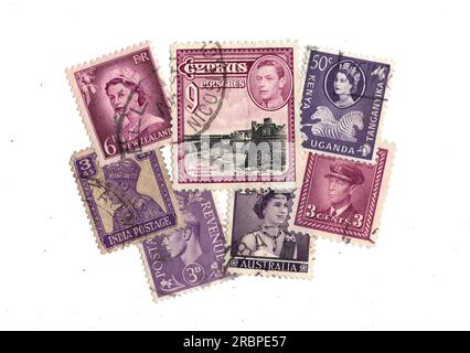 Lila Briefmarken aus dem Britischen Empire auf weißem Hintergrund. Stockfoto