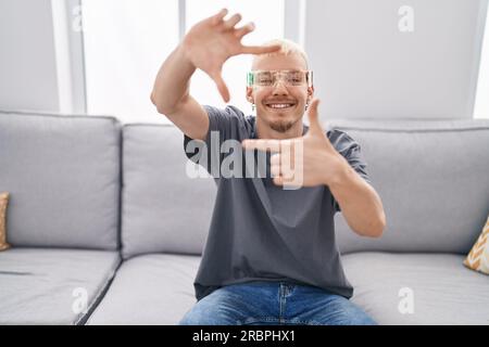 Ein junger weißer Mann, der eine Virtual-Reality-Brille trägt und mit Händen und Fingern mit fröhlichem Gesicht lächelt. Kreativität und fotografisches Konzept. Stockfoto