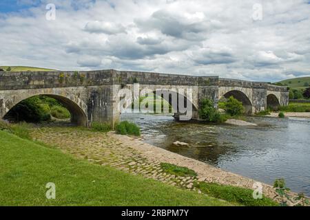 Die Burnsall Bridge in den Yorkshire Dales überquert die River Wharfe mit ihren fünf Bögen und feinen Attiken im Falle einer Überschwemmung Stockfoto