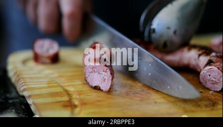 Schneide die Wurst mit dem Messer auf, um Churrasco vom Grill zuzubereiten Stockfoto