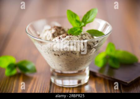 Hausgemachtes Eis mit Stücken geriebener dunkler Schokolade, in einer Schüssel auf einem Holztisch. Stockfoto