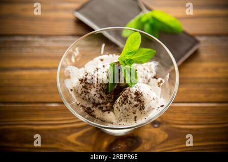 Hausgemachtes Eis mit Stücken geriebener dunkler Schokolade, in einer Schüssel auf einem Holztisch. Stockfoto