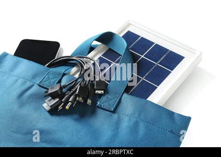 Tasche mit tragbarem Solarmodul, Mobiltelefon und Kabeln auf weißem Hintergrund Stockfoto