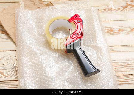 Abroller für Verpackungsband und Luftpolsterfolie auf Holzhintergrund Stockfoto