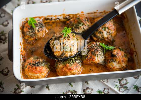 Gekochte Fleischbällchen aus Hackfleisch in einer Sauce in Keramikform auf einem Holztisch Stockfoto