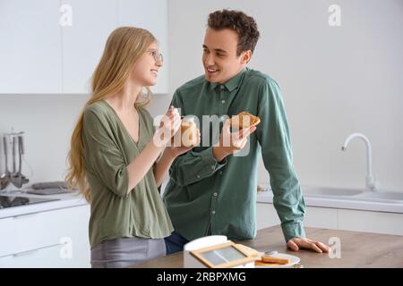 Junge Frau mit Nussbutter in der Hand und hübscher Mann mit Toast in der Küche Stockfoto