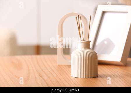 Flasche Reed-Diffusor und leerer Rahmen auf Tisch im Raum, Nahaufnahme Stockfoto