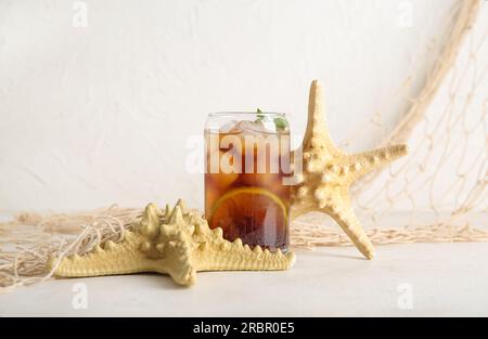 Ein Glas kalter Cuba Libre Cocktail und Seesterne auf weißem Hintergrund Stockfoto