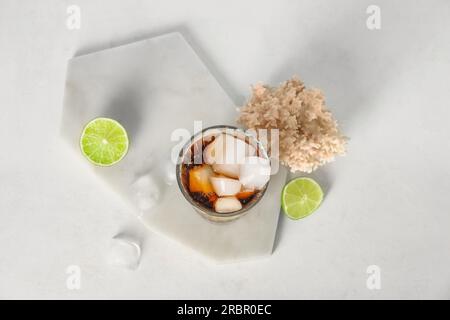 Gehen Sie an Bord mit einem Glas kalten Cuba Libre Cocktail und Korallen auf weißem Hintergrund Stockfoto