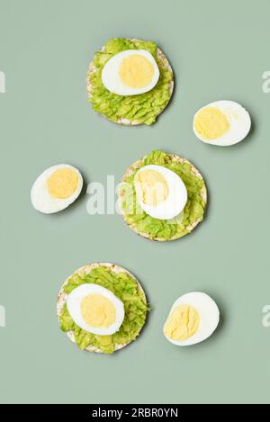 Reiscracker mit gekochten Eiern und Avocado auf grauem Hintergrund Stockfoto