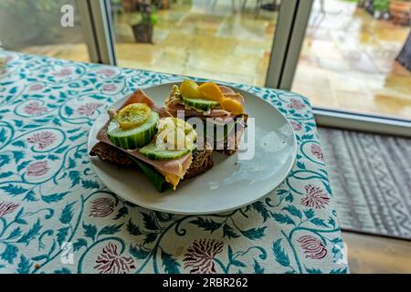 Mittagessen mit Schinkenkäse, Tomaten und Gurken, serviert auf hausgemachtem braunem Brot. Stockfoto