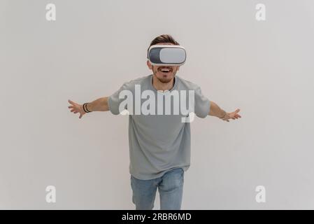Futuristischer Mann mit Virtual-Reality-Brille interagiert mit der Luft auf einem isolierten grauen Hintergrund. Stockfoto