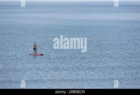 Barmouth, wales, 14. juni 2023 Stand-up Paddle Board Mann Paddleboarding auf blauem Wasser. Stockfoto