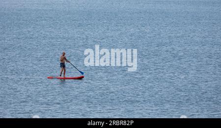 Barmouth, wales, 14. juni 2023 Stand-up Paddle Board Mann Paddleboarding auf blauem Wasser. Stockfoto