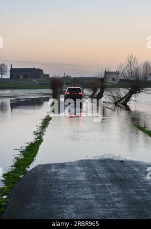 Auto fährt durch die überflutete Straße Godney bei Glastonbury auf den Somerset Levels Stockfoto