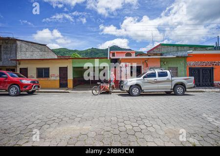 Fahrradwagen und Händler zwischen zwei Toyota Hiluxes in Jinotega, Nicaragua. Hiluxes sind der landesweite Lastwagen von Nicaragua, der von der Polizei und den Bauern benutzt wird Stockfoto