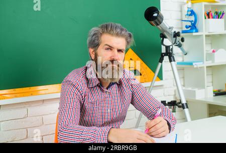 Ein ernster bärtiger Lehrer oder Schüler im Klassenzimmer. Lernen, Bildung, Schulkonzept. Männlicher Lehrer, der Unterricht im Klassenzimmer vorbereitet. Zurück in die Schule Stockfoto