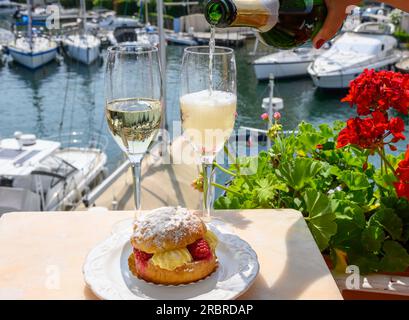 Trinken von französischem Champagner Sekt mit Torte Tarte Tropezienne, Clubparty im Yachthafen Port Grimaud bei Saint-Tropez, French Ri Stockfoto