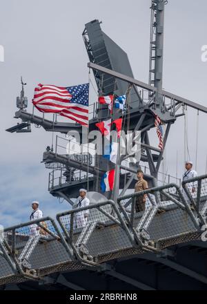 NORFOLK, VA - Matrosen und Marines besteigen die Schienen, während das Amphibienschiff USS Bataan (LHD 5) die Naval Station Norfolk für einen geplanten Einsatz am 10. Juli 2023 verlässt. USA Marines und Matrosen der Bataan Amphibious Ready Group (BAT ARG) / 26. Marine Expeditionary Unit (MEU) (Special Operations Capable) (SOC) verließen Norfolk, Virginia, und Camp Lejeune, North Carolina, nach Abschluss eines umfassenden neunmonatigen Trainingsprogramms. (USA Navy Video von Mass Communication Specialist 3. Class Manvir Gill) Stockfoto