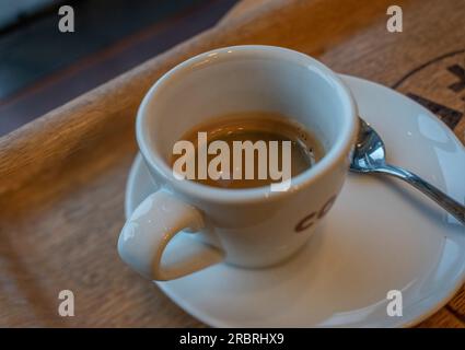 Nahaufnahme von heißem Espresso mit weißer Tasse auf schwarzem Holztisch, Draufsicht Stockfoto