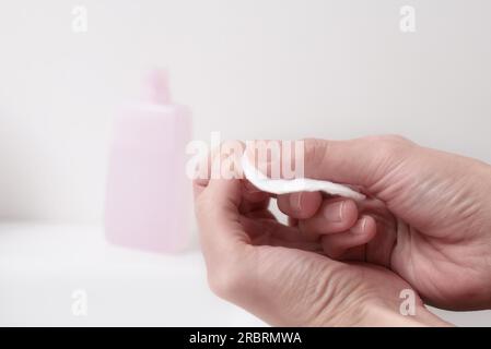 Frau entfernt Nagellack mit Aceton auf einem kleinen Wattepad am Rand eines Handbeckens, während sie sich um ihre Nägel und Nagelhäute in einem gesunden und Stockfoto