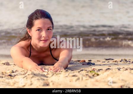 Wunderschönes weibliches Model liegt im Sand am Strand Stockfoto