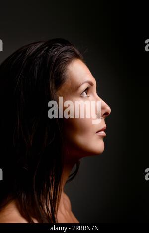 Höhenplan einer schönen schweren ruhige junge Frau stehen im Schatten ins Licht mit einem Blick der Sehnsucht und Einsamkeit starrte Stockfoto