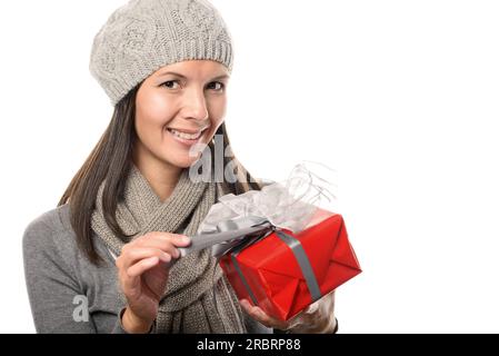 Nahaufnahme der lächelnden jungen Frau in der Geschenkbox der Wintermode, während sie auf die Kamera blickt, isoliert auf weißem Hintergrund Stockfoto