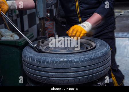 Nicht erkennbarer Mann, der Reifen von Felge trennt Stockfoto