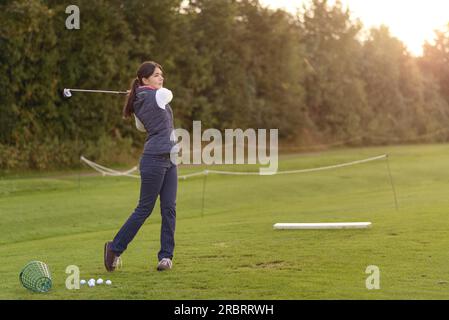 Weibliche Golfer auf der driving Range an einem späten Nachmittag Tag stehen, stehen in der Finish-position Stockfoto