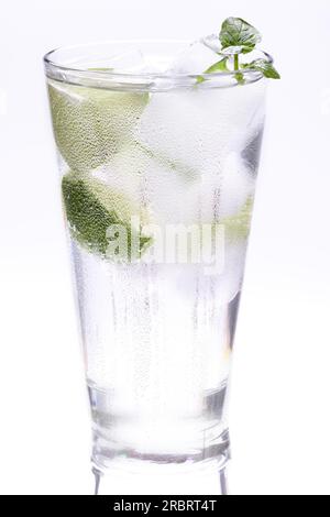Ein großes Glas kaltes Eiswasser mit Minzblättern und Limettenscheiben auf weißem Hintergrund mit Reflexion auf dem Tisch Stockfoto