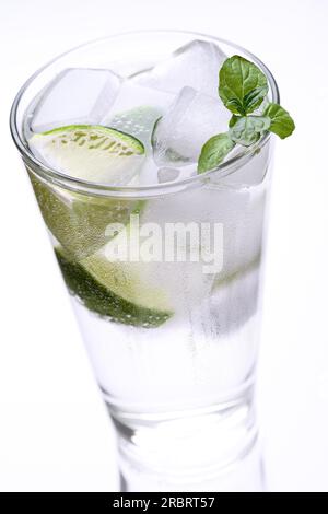 Ein großes Glas kaltes Eiswasser mit Minzblättern und Limettenscheiben auf weißem Hintergrund mit Reflexion auf dem Tisch Stockfoto