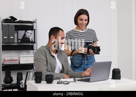 Junge professionelle Fotografen mit Kamera, die auf einem Laptop im modernen Fotostudio arbeiten Stockfoto