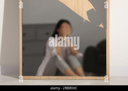 Psychische Probleme. Verschwommenes Spiegelbild einer depressiven Frau im zerbrochenen Innenspiegel Stockfoto
