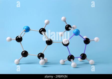 Nikotinmolekül auf hellblauem Hintergrund. Chemisches Modell Stockfoto