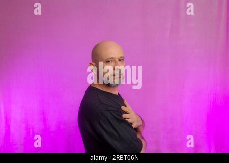 Porträt eines ernsthaften 50-jährigen Mannes mit Bart und kahlem Kopf. Isoliert auf pinkfarbenem Hintergrund. Stockfoto