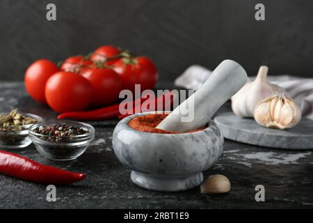 Mörtel mit roter Currypaste und Zutaten auf einem schwarz strukturierten Tisch Stockfoto