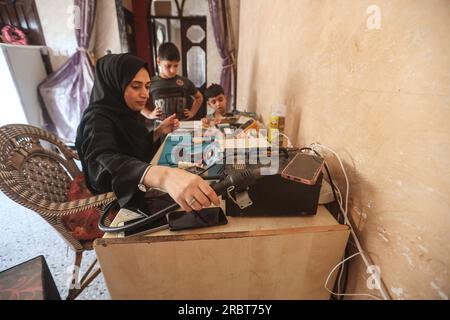 Eine palästinensische Frau Walaa Hammad repariert Smartphones in der Empfangshalle ihrer Familie im Al-Shati-Flüchtlingslager in West Gaza City. Die palästinensische Walaa Hammad, 26, startete ihr Projekt zur Reparatur von Smartphones für Frauen nur in dem bescheidenen und einfachen Haus ihrer Familie im Zentrum des Flüchtlingslagers Al-Shati westlich von Gaza. Hammad bietet einen Telefonreparaturservice für Frauen an, die Angst davor haben, männlichen Technikern ihre Fotos und Konten auf Social-Media-Plattformen zeigen zu lassen. Und mit den schlechten und schwierigen wirtschaftlichen Bedingungen, die die Bewohner des Gazastreifens erleiden, der Zunahme der Arbeitslosigkeit und der l Stockfoto