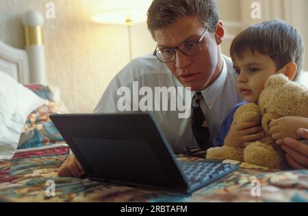 Vater und Sohn sahen einen Laptop auf dem Bett Stockfoto