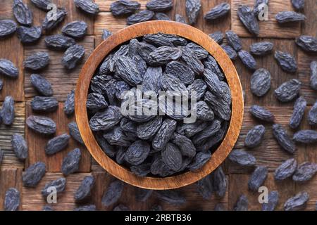 Blaue Rosinen, getrocknete Weintrauben in Schüssel auf Holztischhintergrund. Stockfoto