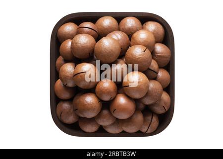 Geschälte Macadamianüsse in einer Holzschüssel. Vegetarisches Essen isoliert auf Weiß. Stockfoto